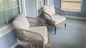 A room with two wicker chairs and a large window providing a view of a yard. - Peaceful 3-Bedroom Retreat in Huger, SC – Gateway to the Lowcountry (Huger)