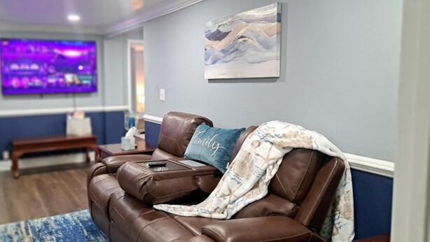 A living room with a brown leather sofa, a blanket, and a remote control. - Peaceful 3-Bedroom Retreat in Huger, SC – Gateway to the Lowcountry (Huger)