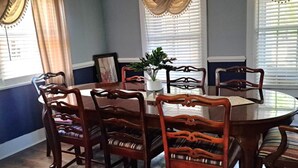 A dining room with a round table and six wooden chairs with striped cushions. - Peaceful 3-Bedroom Retreat in Huger, SC – Gateway to the Lowcountry (Huger)