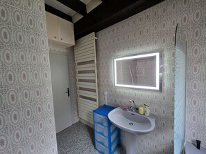 Bathroom features a classic sink, mirror, and window, with a storage unit and decorative wall pattern.