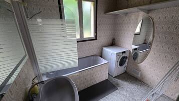 Un baño pequeño con lavabo, lavadora y espejo.