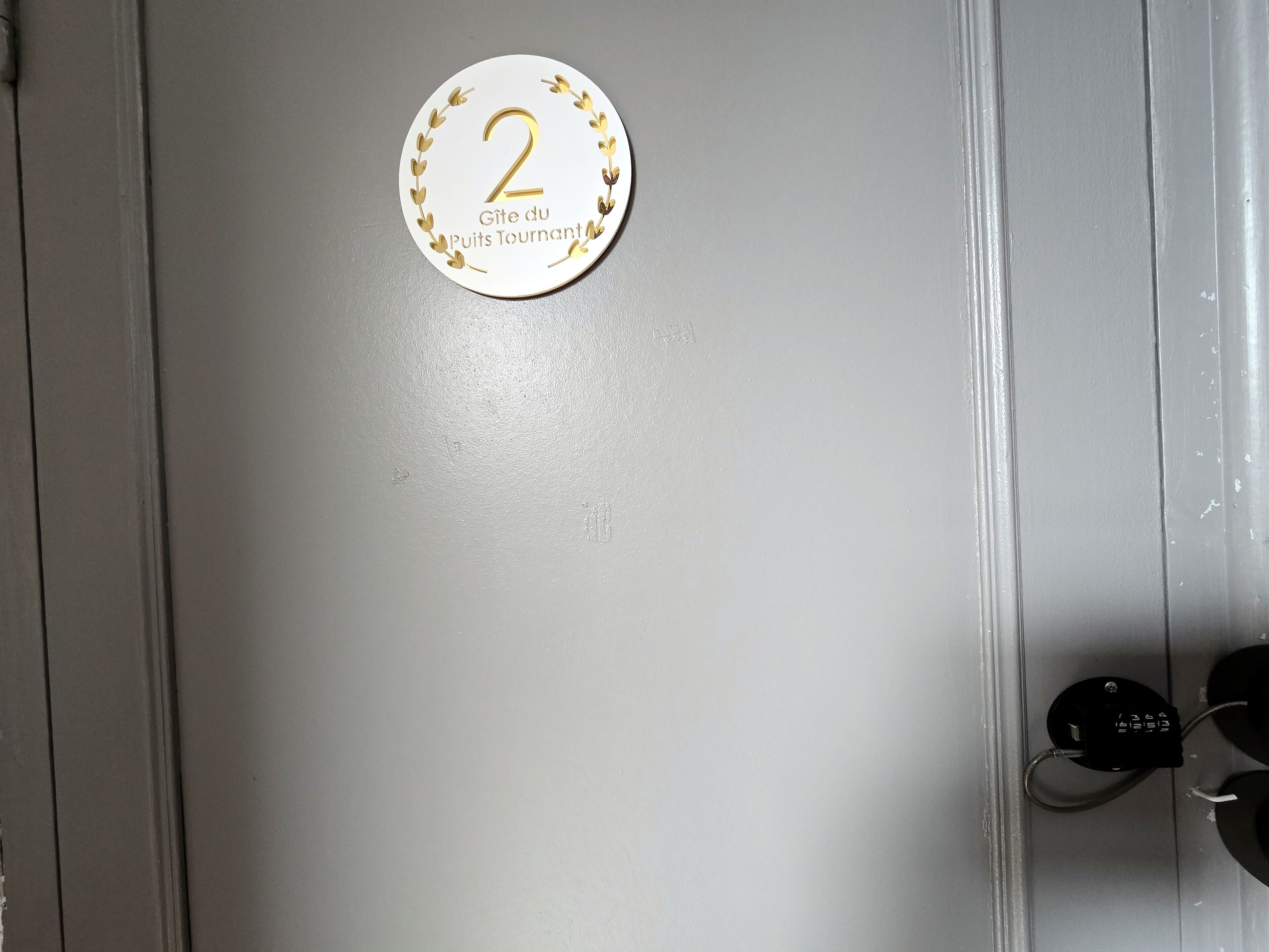 Eine Tür mit einer Nummernschild, das Zimmer Nummer 2 anzeigt, und einer Plakette mit französischem Text.