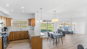 Een moderne keuken met houten kasten, een centraal eiland en een zithoek met een bank en stoelen.