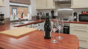 A modern kitchen with wooden countertops, stainless steel appliances, and a built-in oven. - Gressingham View Lodge (Carnforth)
