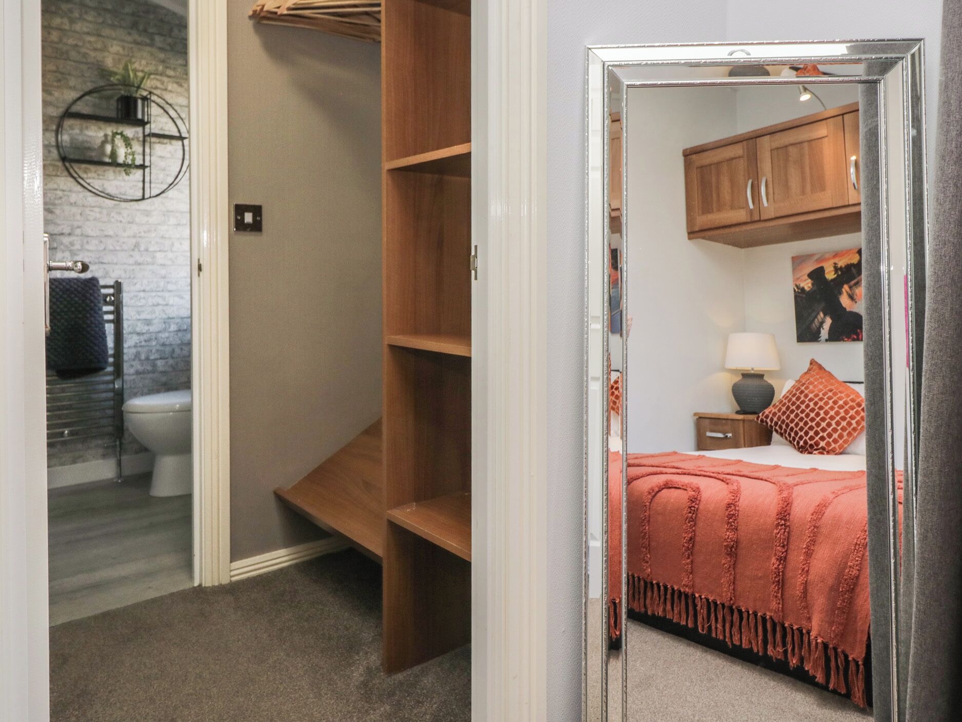A bedroom with a bed, a nightstand, a lamp, a painting, and a wooden cabinet.
