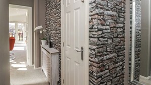 A hallway with a stone wall, a white door, and a mirror on the right. - Gressingham View Lodge (Carnforth)