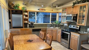 A modern kitchen with wooden cabinets, stainless steel appliances, and a dining area with a wooden table and chairs. - Water front, private beach, steps from down town Hoodsport with lots of parking. (Hoodsport)