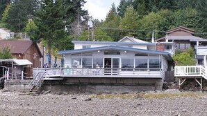 A waterfront building with a covered deck and a staircase leading to the entrance. - Water front, private beach, steps from down town Hoodsport with lots of parking. (Hoodsport)