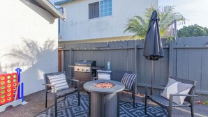 A backyard with a grill, outdoor seating, and a fire pit.