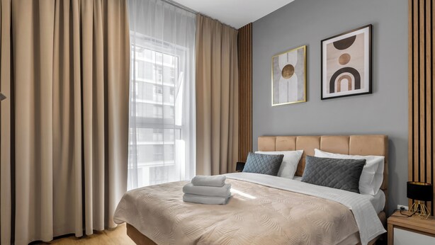 A modern hotel room with a large bed, beige curtains, and two framed artworks on the wall. - Varsovia Comfort 340 (Warszawa)