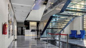 A modern lobby with a reception desk, a glass staircase, and a water feature. - Varsovia Comfort 340 (Warszawa)