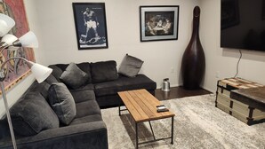 A living room with a sectional sofa, a coffee table, a TV, and framed pictures on the wall. - Charming 1-bedroom cabin in amazing Camp Verde with WiFi, AC, very spacious (Camp Verde)