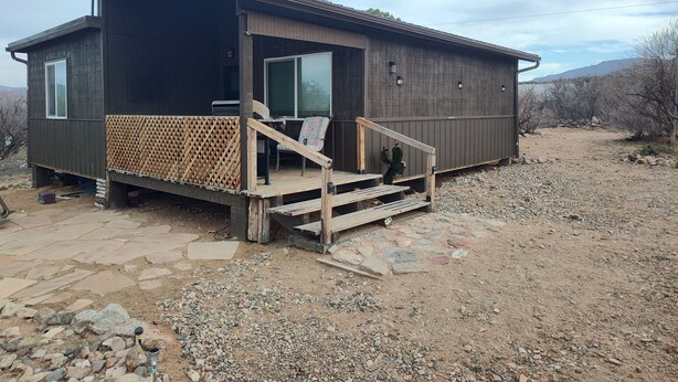 A small, dark-colored cabin with a wooden deck and a single chair. - Charming 1-bedroom cabin in amazing Camp Verde with WiFi, AC, very spacious (Camp Verde)