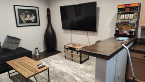 A living room with a sofa, a coffee table, a TV, a large vase, and a slot machine. - Charming 1-bedroom cabin in amazing Camp Verde with WiFi, AC, very spacious (Camp Verde)