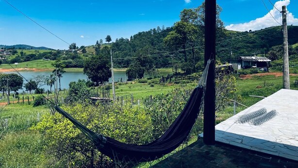 A hammock in a covered outdoor area overlooking a lake and greenery. - Cozy farm in front of the dam, for water sports and fishing. (Serrinha Bragança Paulista)