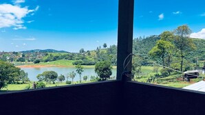 A room with a view of a lake, surrounded by greenery and hills. - Cozy farm in front of the dam, for water sports and fishing. (Serrinha Bragança Paulista)
