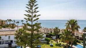 Un resort con piscina, palmeras y vista al mar.