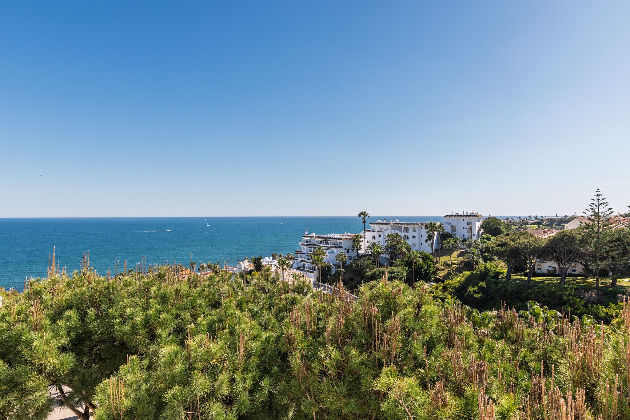 Vista sulla costa con edifici bianchi, cielo sereno e vista sul mare.