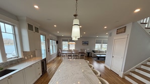 A spacious kitchen with a large island, wooden flooring, and white cabinetry. - Luxury Waterfront Home Private Dock, Stunning Views & Sleeps 14 (South Kingstown)