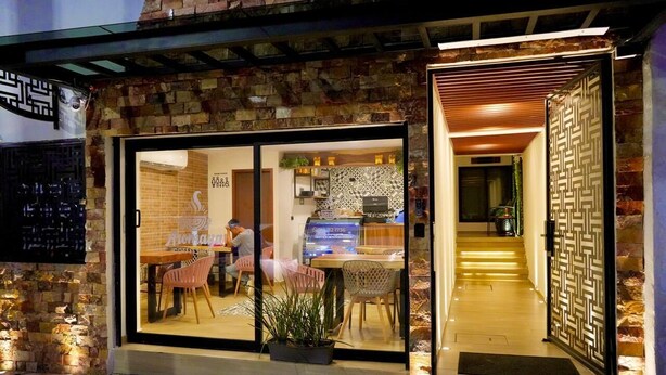A restaurant with a stone facade, large glass doors, and a modern interior with a patterned backsplash. - Hotel Palenque Premier (Palenque)