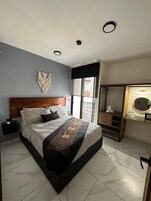 Un dormitorio moderno con una cama grande, cabecera de madera, tocador con espejo y armario.