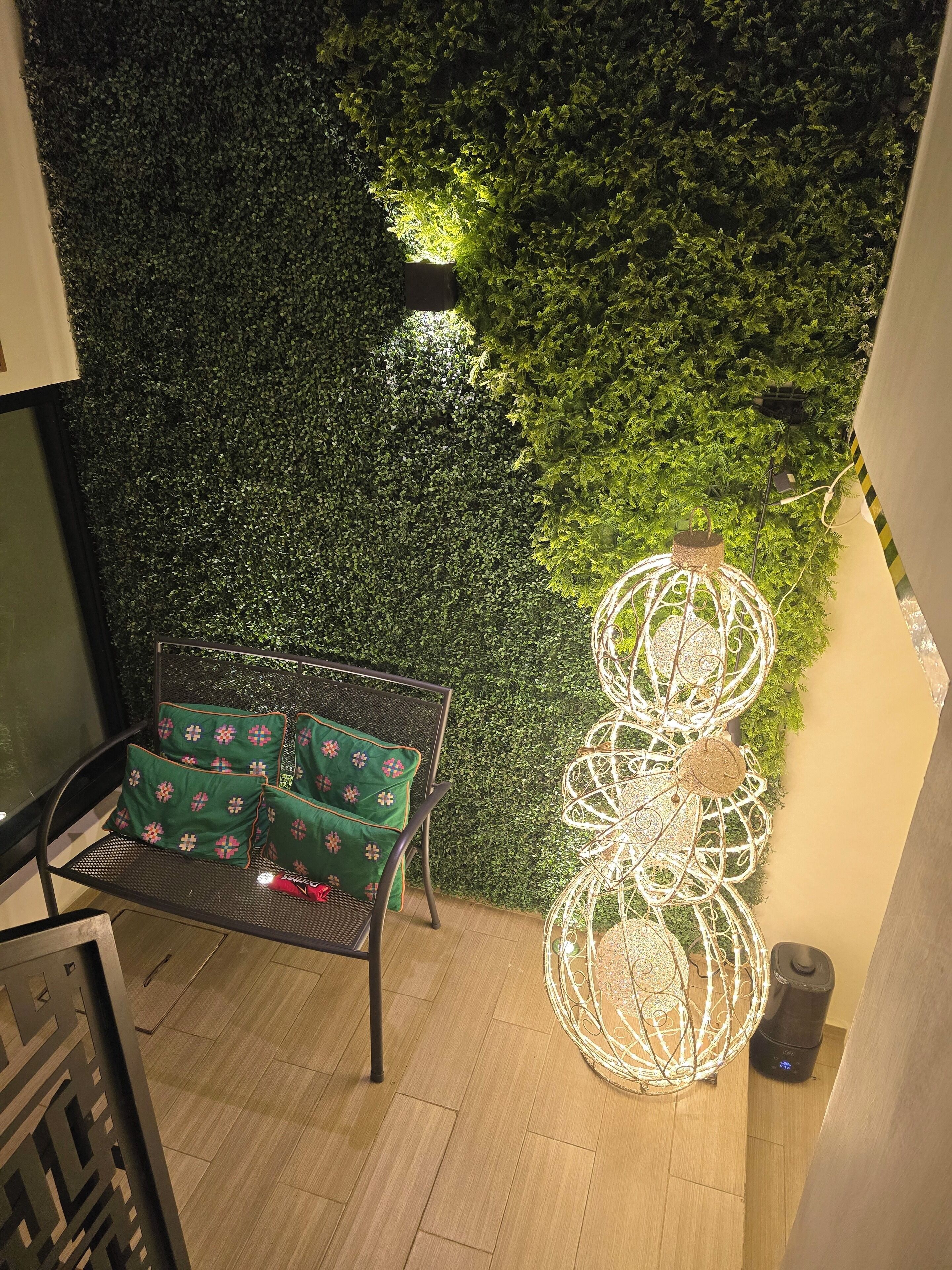 A corner of a room with a green wall, a metal chair with green cushions, and a white decorative light fixture.