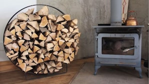 A room with a wood stove and a large stack of firewood.