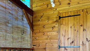 A wooden deck with a table and chairs, a lantern, and a door. - Gîte Santa Maria (Grand-Bourg)