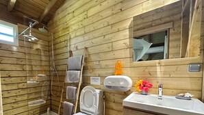 A wooden cabin bathroom with a shower, toilet, sink, and a mirror. - Gîte Santa Maria (Grand-Bourg)