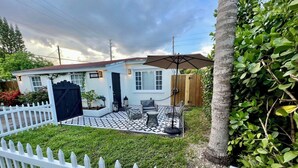 A house with a white picket fence, a tiled patio, and a small garden.