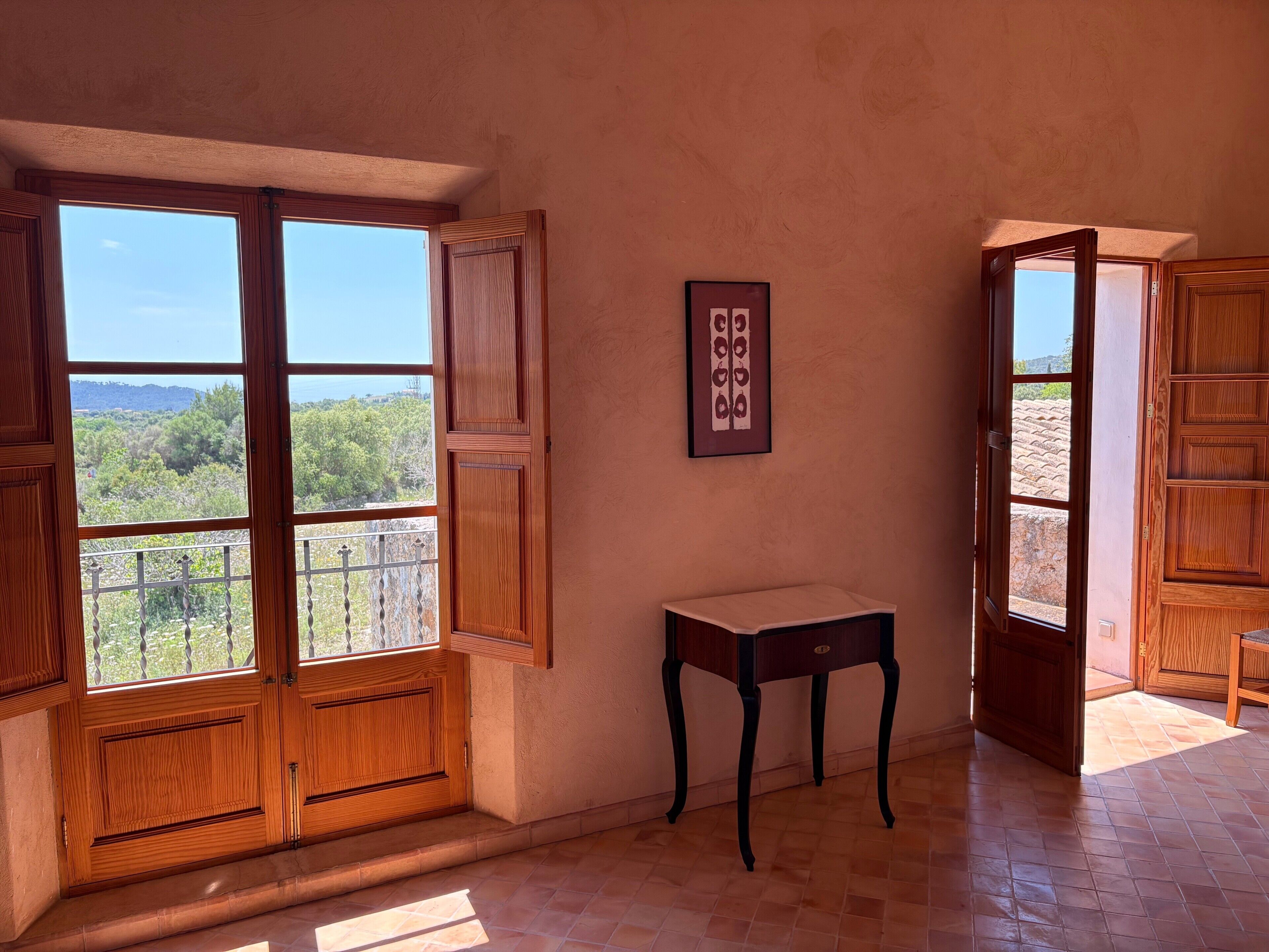 A room with wooden doors, a small table, and a framed picture on the wall.