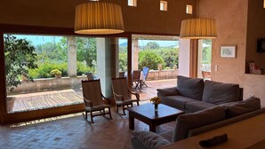 A spacious living area with a large window, a sofa, two rocking chairs, and a coffee table. - Country House 'Son Gener' with Private Pool, Private Terrace and Wi-Fi (Son Servera)