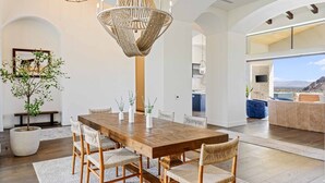 A spacious dining area with a wooden table and chairs, a large woven chandelier, and a view of the outdoors. - Poolside Oasis, Golf Paradise, Hot Tub, Spa, Views (La Quinta)