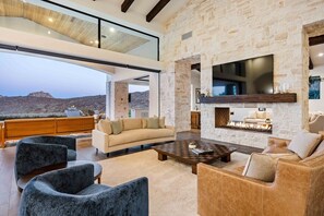 A spacious living area with a stone wall, a fireplace, and a large flat-screen TV.