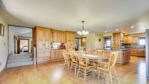 A spacious kitchen with wooden cabinets, a large dining table, and a chandelier.