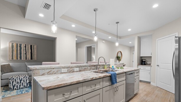 A modern kitchen with a marble countertop, stainless steel appliances, and pendant lighting.