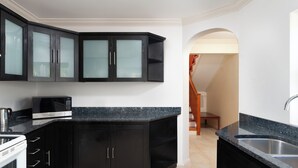 A modern kitchen with dark cabinetry, a microwave, and a sink.