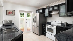 A modern kitchen with stainless steel appliances, black cabinets, and a double sink.