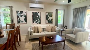 A living room with a sofa, two armchairs, a coffee table, and a dining area with chairs and a table.