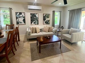 A living room with a sofa, two armchairs, a coffee table, and a dining area with chairs and a table.