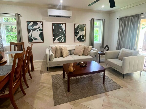 Una sala de estar con sofá, dos sillones, una mesita de centro y un comedor con sillas y una mesa.