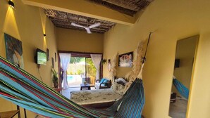 Un hamac dans une chambre avec vue sur la piscine, un ventilateur de plafond et un grand miroir.