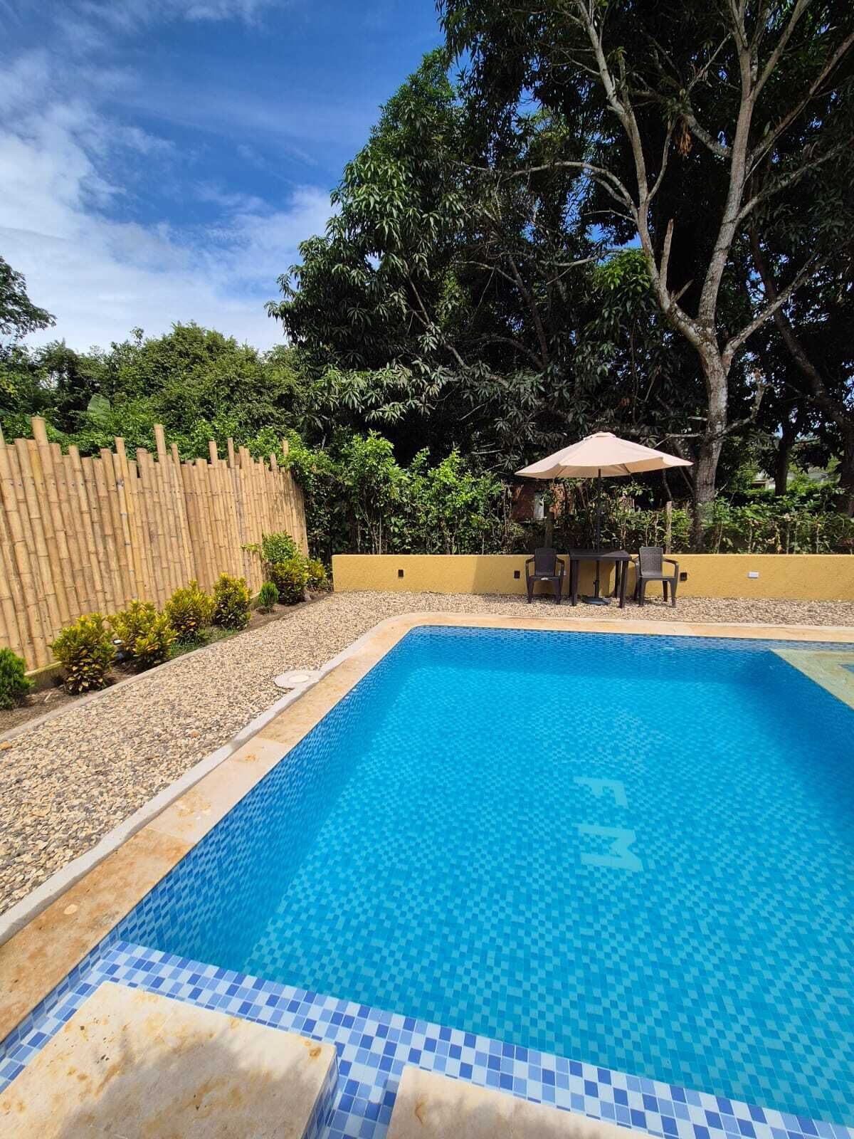 A rectangular swimming pool with a tiled edge, surrounded by a wooden fence and a yellow wall.