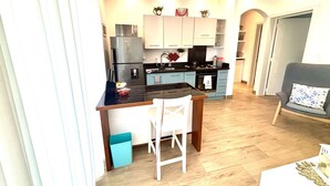 A modern kitchen with a central island, light blue cabinets, and stainless steel appliances. - Apartment in a residence facing the sea (Las Terrenas)