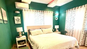 A bedroom with a bed, nightstands, a green rug, and a ceiling fan. - Apartment in a residence facing the sea (Las Terrenas)