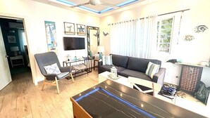 A living room with a sofa, armchair, coffee table, and a flat-screen TV. - Apartment in a residence facing the sea (Las Terrenas)