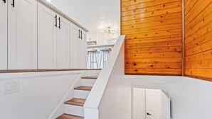 Una escalera conduce a una cocina con armarios blancos y detalles de madera.