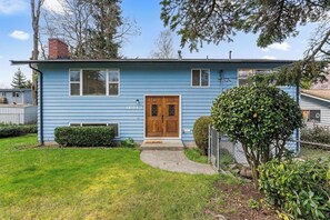 A single-story blue house with a wooden front door and a number '16513' on the side.