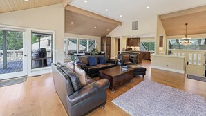 A spacious living area with a large leather sofa, a wooden coffee table, and a view of the outdoors through large sliding glass doors. - 20 Aspen - Elegant & Updated & Perfect for Family! SHARC, Hot Tub (Bend)