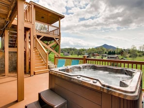 Una terraza de madera con un jacuzzi y una escalera que sube a un balcón.